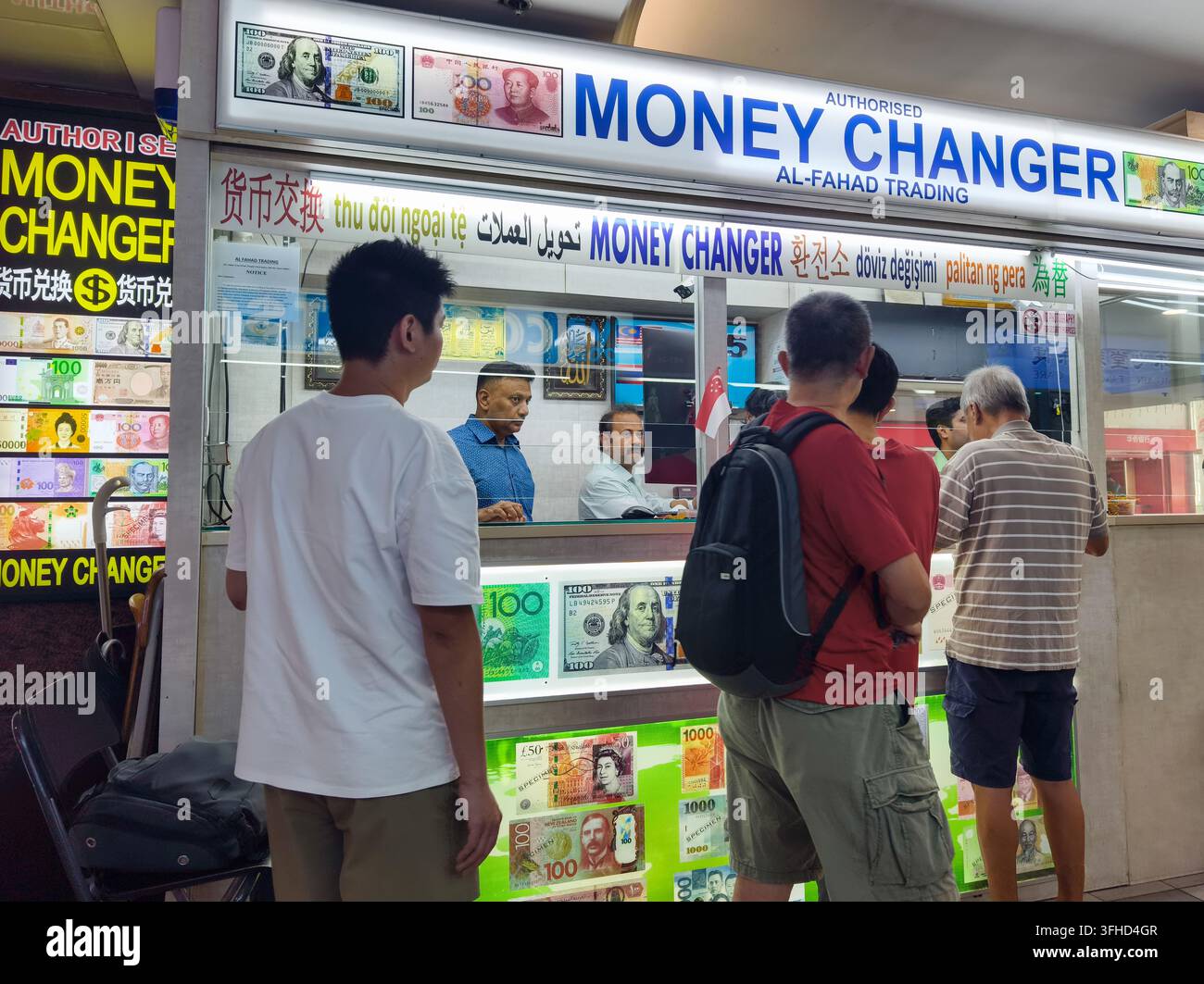 Clienti in fila davanti a un banco di cambio autorizzato, Al-Fahad Trading situato al People's Park Centre di Singapore. Foto Stock