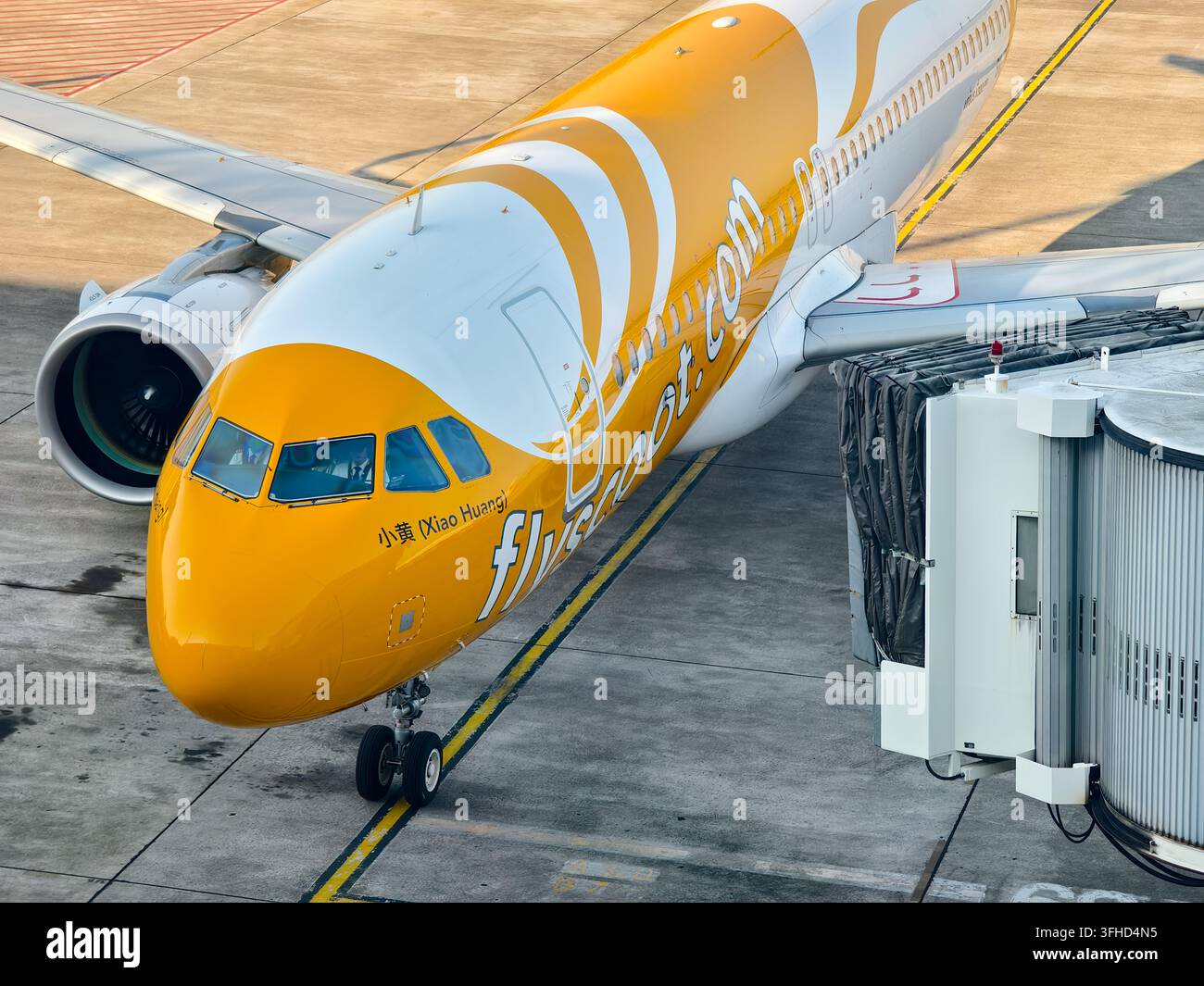 Airbus A320 gestito dalla compagnia aerea a basso costo Scoot parcheggiato al gate dell'aeroporto di Semarang collegato a una passerella di imbarco Foto Stock