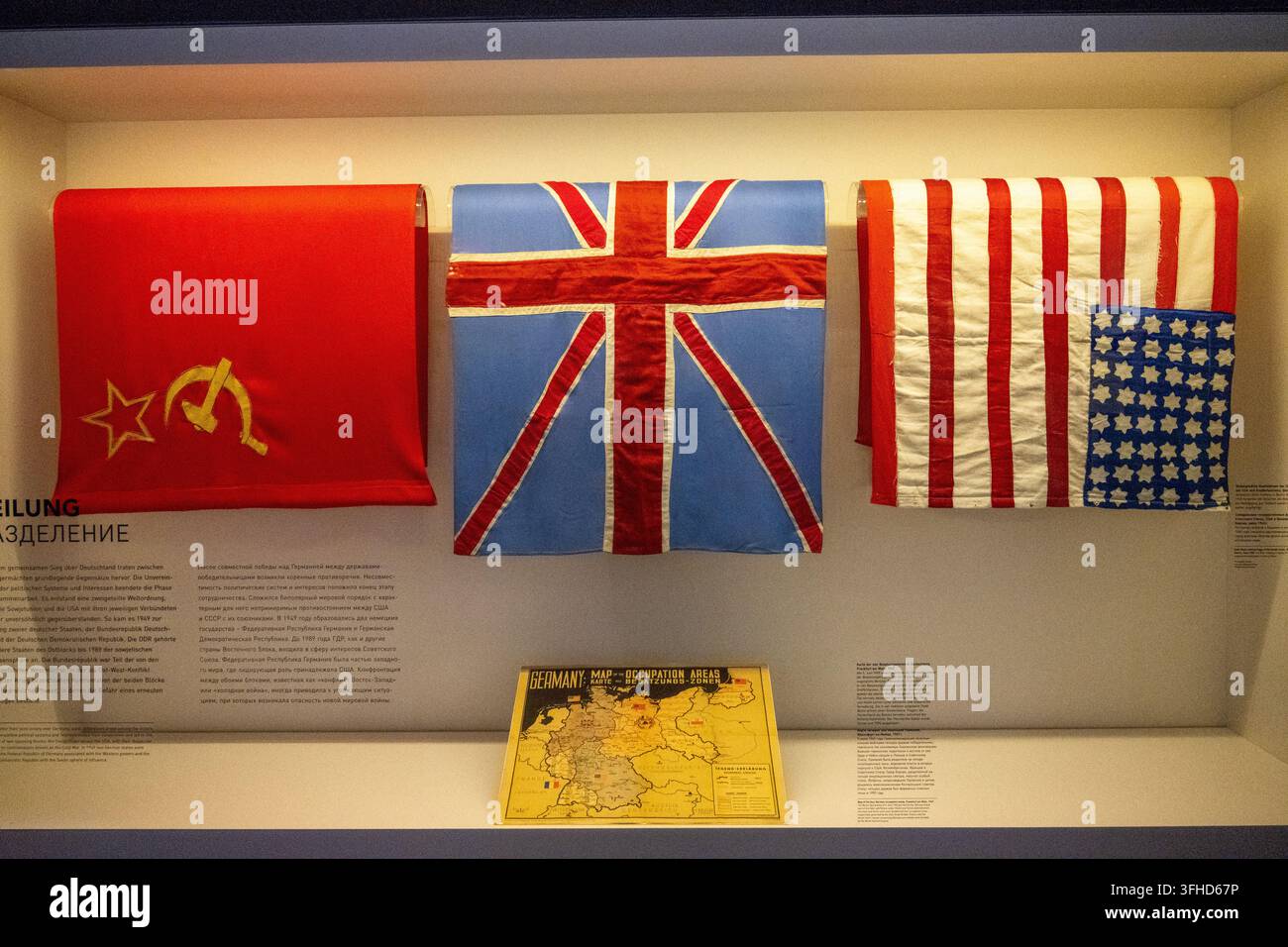 Berlino, Germania - 8 nov 25: Bandiere sovietica, britannica e americana con mappa di occupazione esposte al Museo Berlin-Karlshorst. Foto Stock