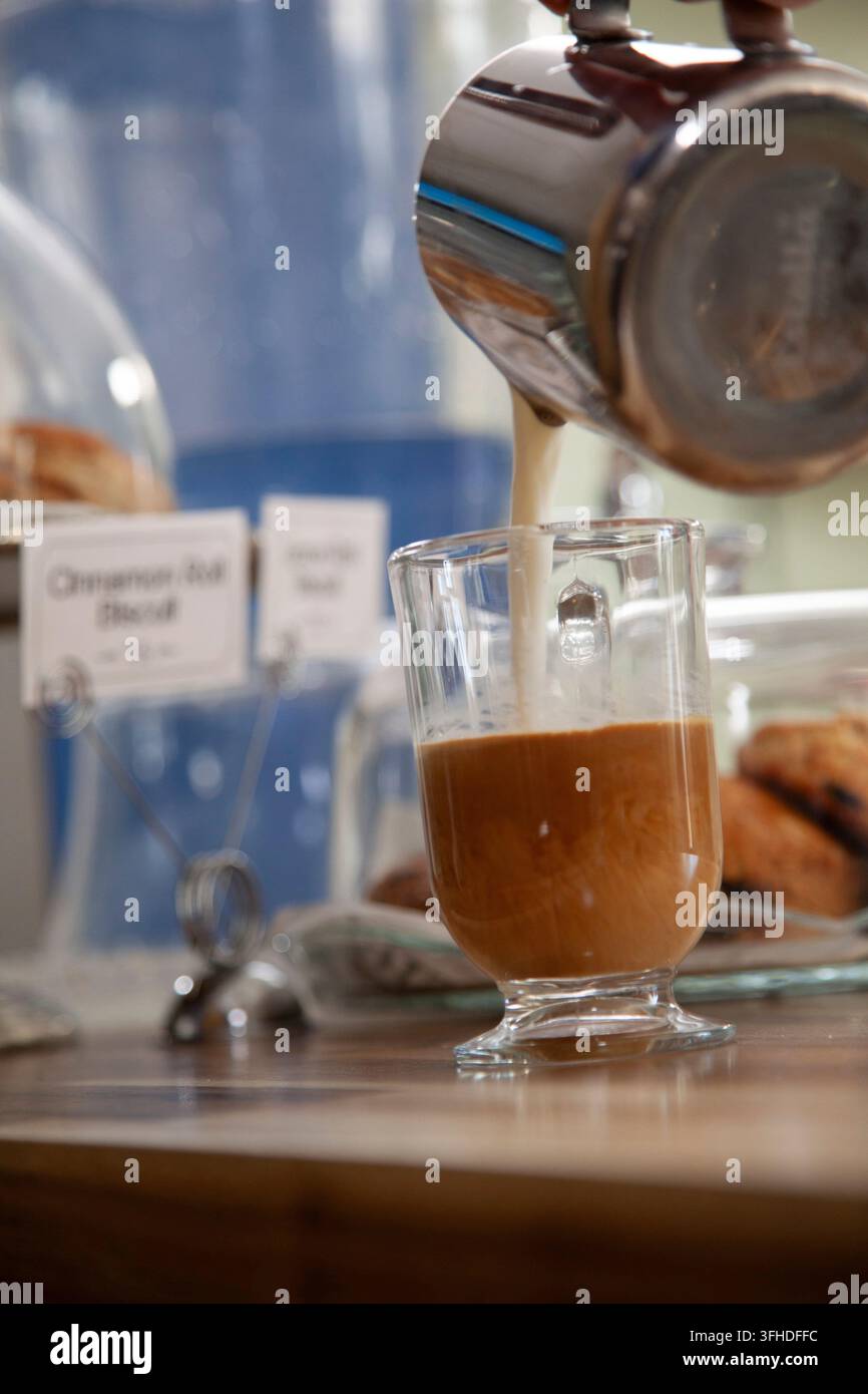 Versare latte sull'espresso Foto Stock