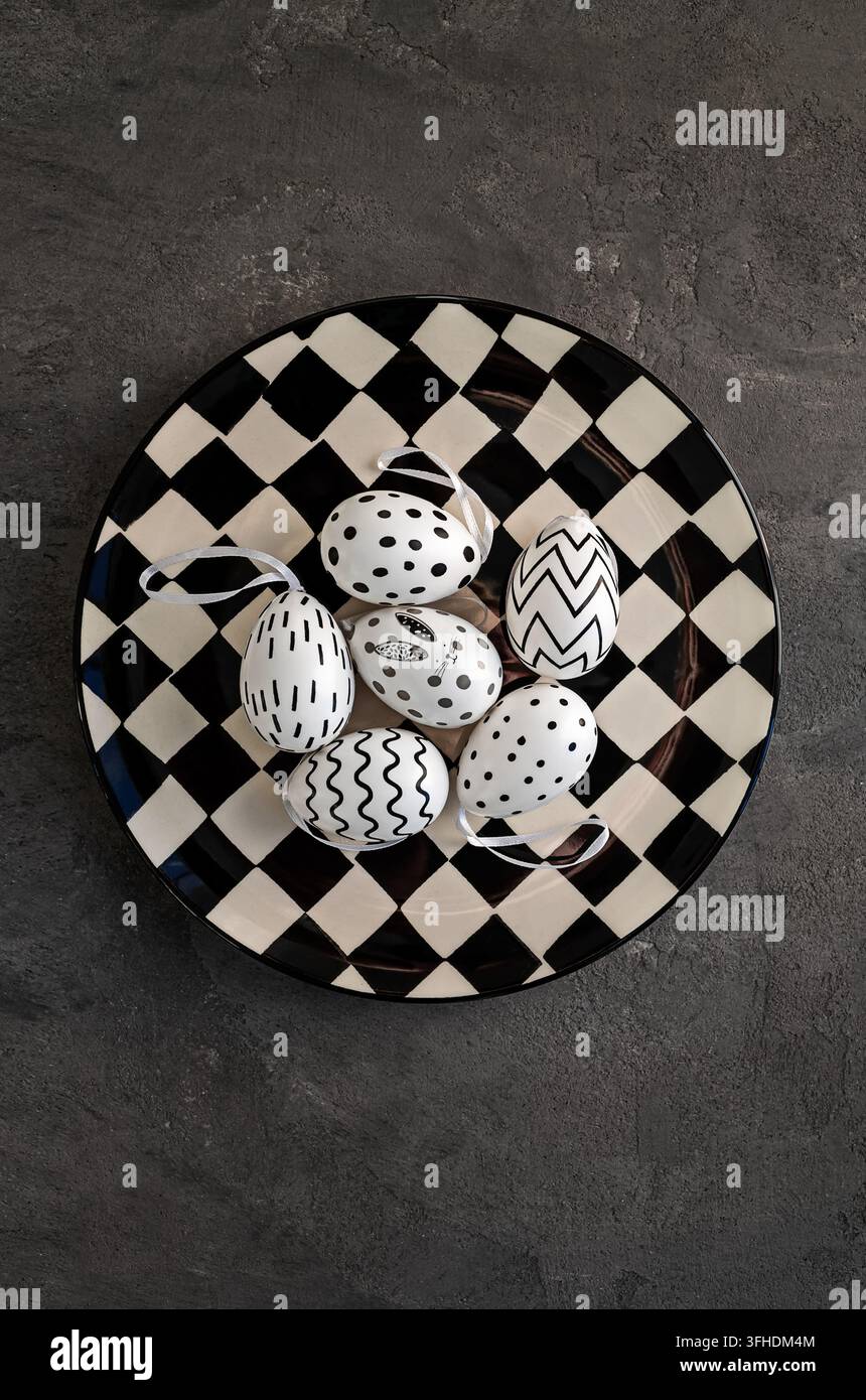 Uova di Pasqua decorative su un piatto bianco e nero Foto Stock