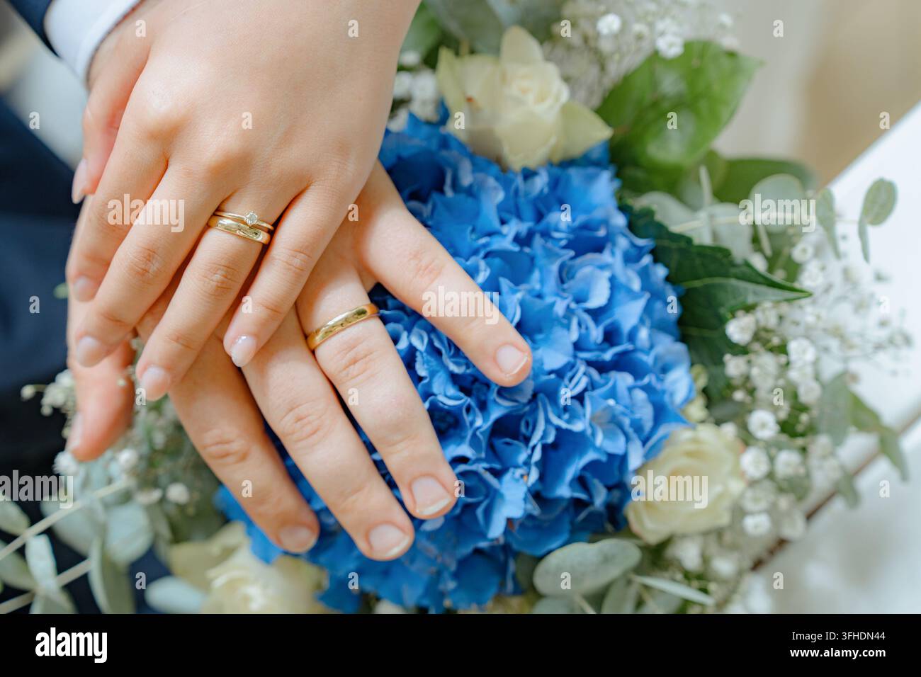 Fedi nuziali che tengono le mani, in un mazzo di fiori, con fedi nuziali, mazzo con blu e, da una prospettiva ravvicinata, con accenti blu e bianchi Foto Stock