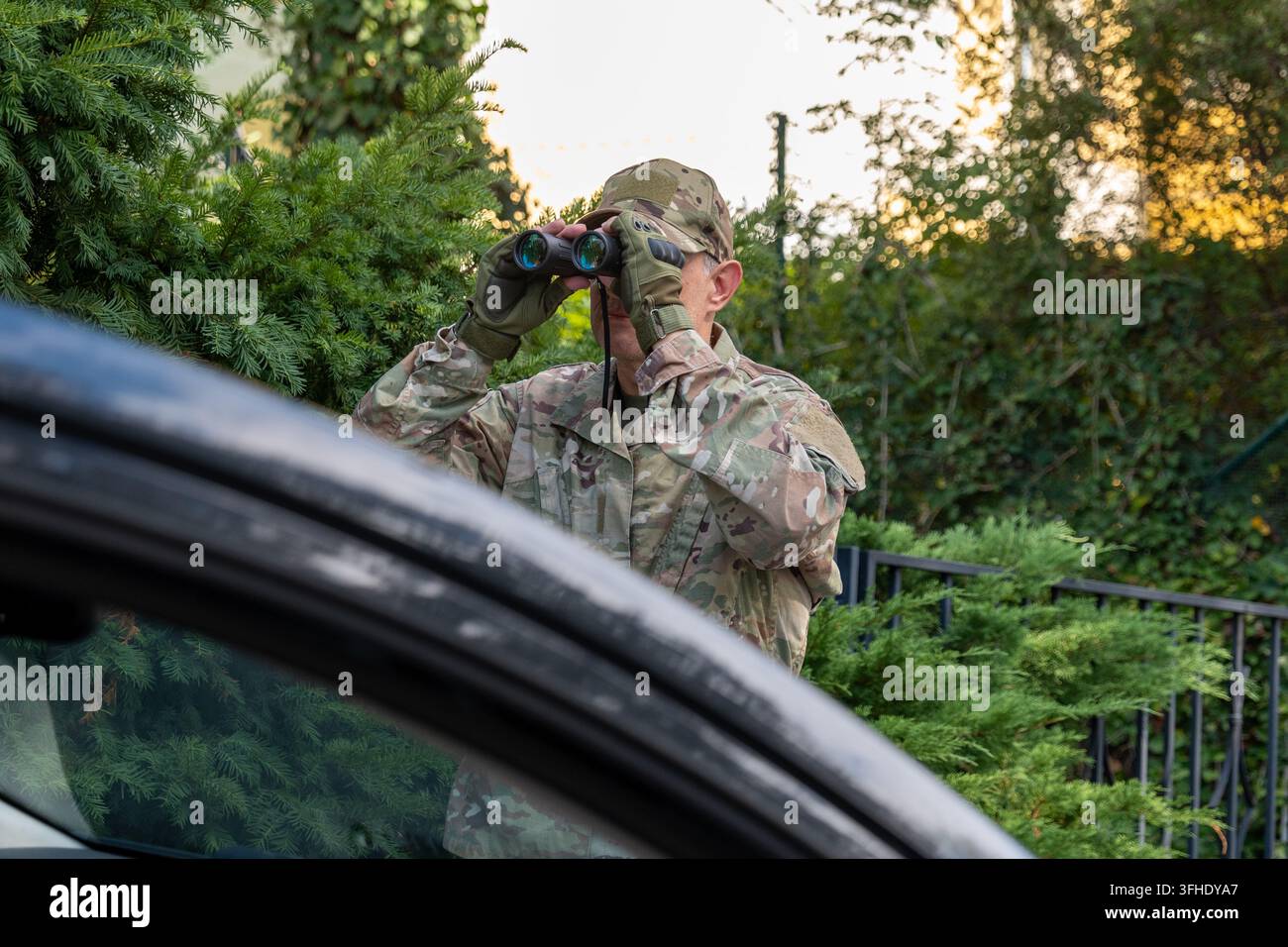Operatore militare conduce una sorveglianza segreta e raccoglie informazioni durante una missione di intelligence in un ambiente esterno Foto Stock