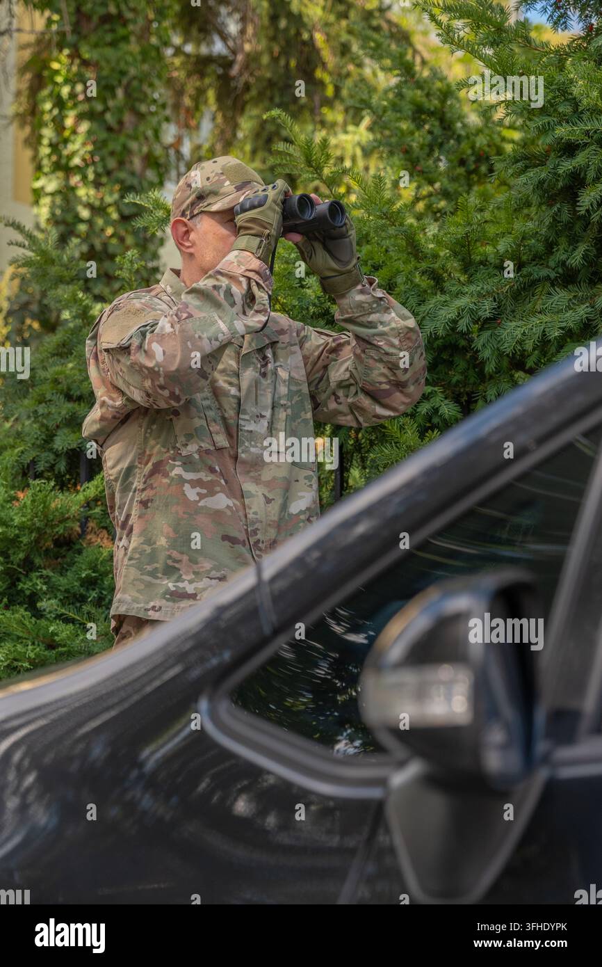 Esploratore militare conduce una sorveglianza segreta vicino a un veicolo raccogliendo informazioni per un'operazione speciale Foto Stock