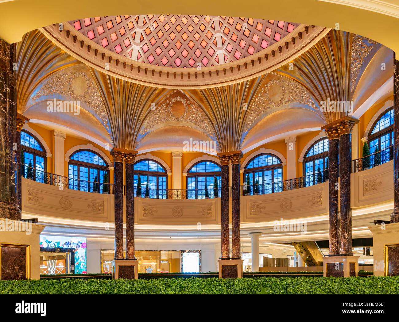 Colonne di marmo lucidate sostengono un soffitto a volta ornato con una cupola di vetrate colorate sopra un interno commerciale su più livelli. Foto Stock