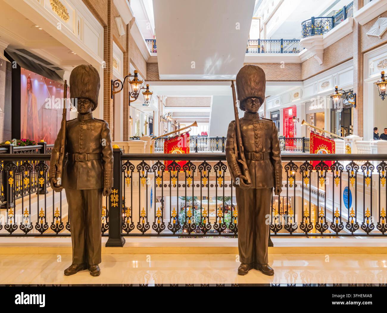 Due statue in bronzo a grandezza naturale di guardie britanniche che indossano cappelli di pelle d'orso e tengono fucili stanno sull'attenti su un balcone del centro commerciale. Foto Stock