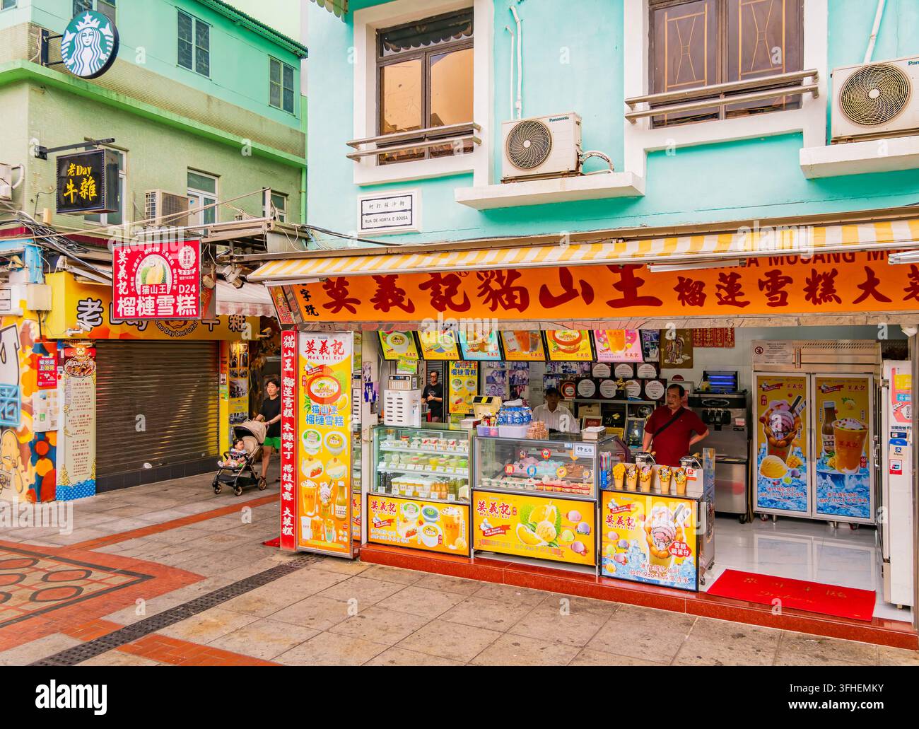 Macao, Cina, 16 apr. 2024 – Una vetrina colorata con insegne giallo brillante e tende a strisce mostra varie prelibatezze di gelato e congelatore Foto Stock