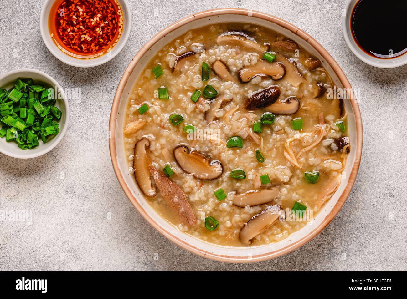 Zuppa di riso congee densa con pollo, funghi shiitake e cipollotti, vista dall'alto. Foto Stock