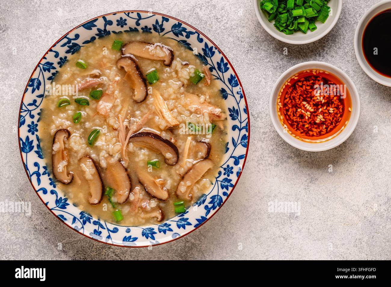 Zuppa di riso congee densa con pollo, funghi shiitake e cipollotti, vista dall'alto. Foto Stock