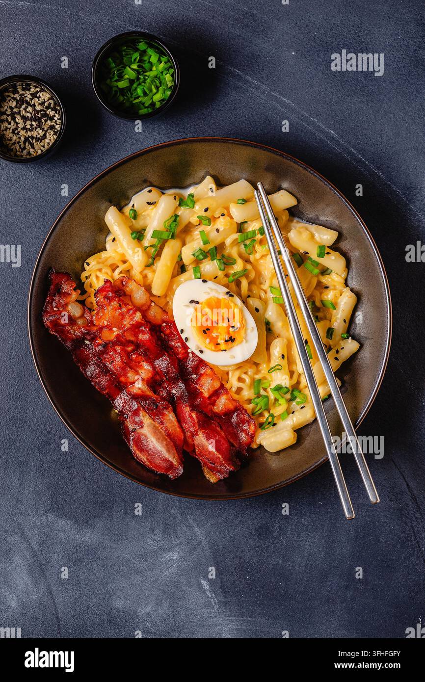Cibo di strada coreano - rapokki cremoso servito con pancetta e uovo, vista dall'alto. Foto Stock