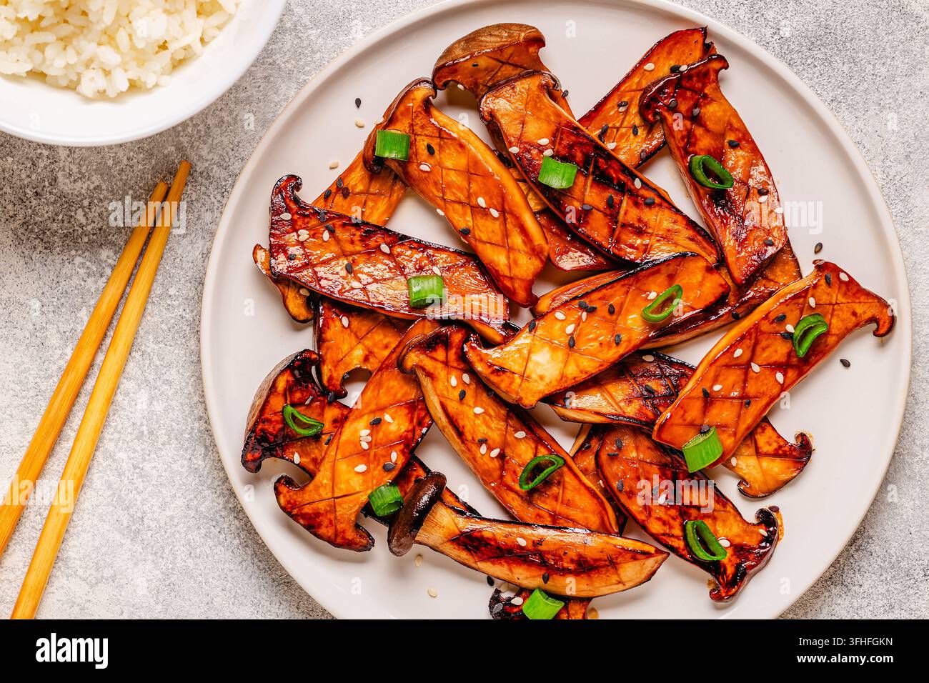 Funghi eryngii fritti o pleuroti con una guarnizione di cipollotti e semi di sesamo. Foto Stock
