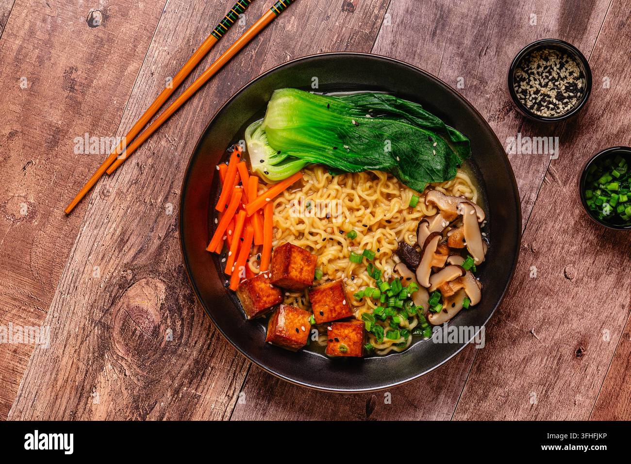 Zuppa miso ramen con noodles servita con tofu, bok choy, carote e funghi in una ciotola. Foto Stock
