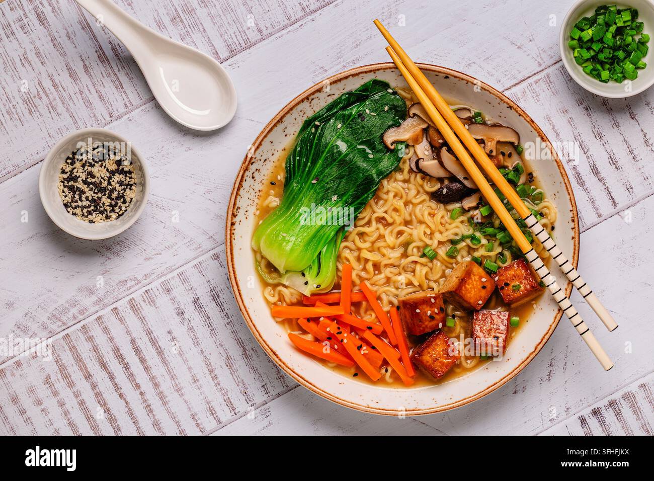 Zuppa miso ramen con noodles servita con tofu, bok choy, carote e funghi in una ciotola. Foto Stock