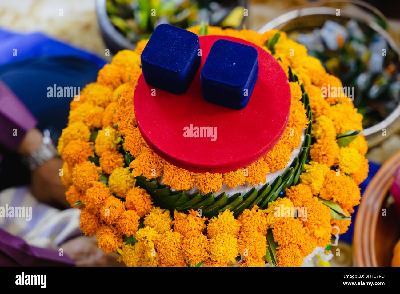Due scatoline per anelli blu posate su una vivace composizione floreale di calendule per un matrimonio Foto Stock