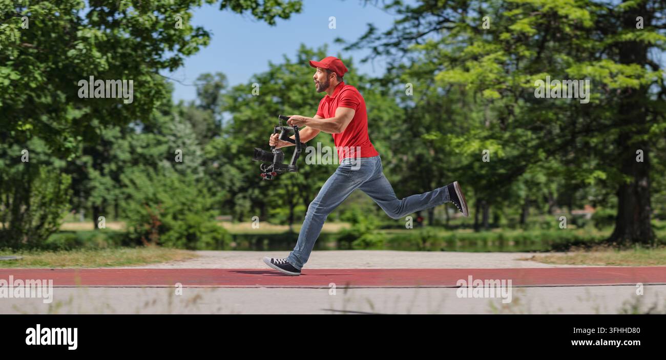 Operatore di telecamera che corre con uno stabilizzatore e registra in un parco Foto Stock