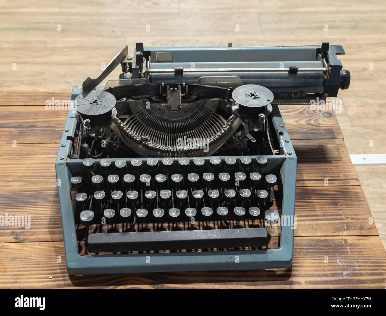 Una macchina da scrivere meccanica antica poggia su una superficie in legno stagionato, fungendo da oggetto simbolico per la letteratura e il giornalismo che riflette la storia Foto Stock