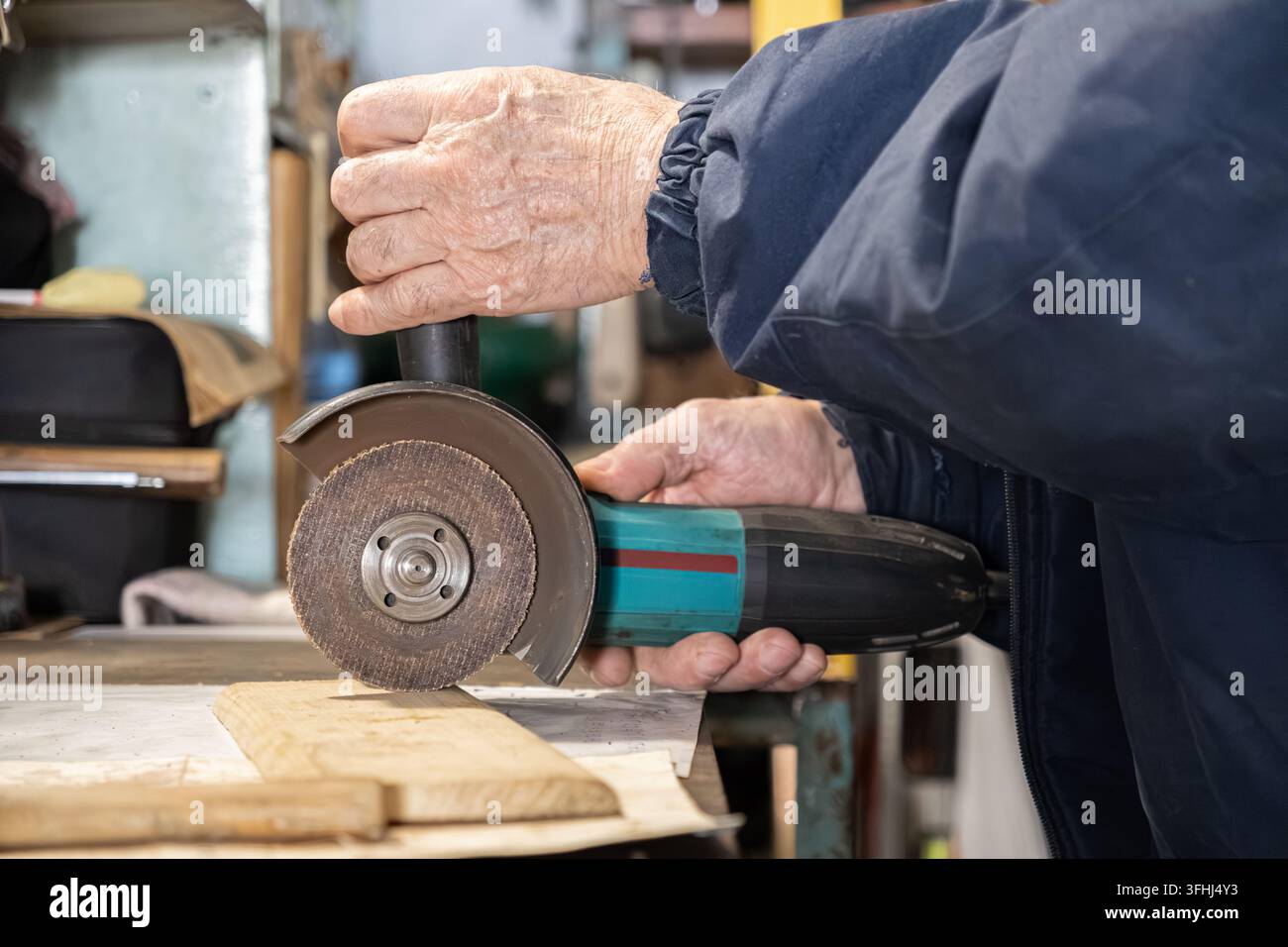 Un falegname esperto maneggia un utensile elettrico portatile per levigare il legno, evidenziando l'esperienza e la concentrazione tecnica necessarie per la costruzione e Foto Stock