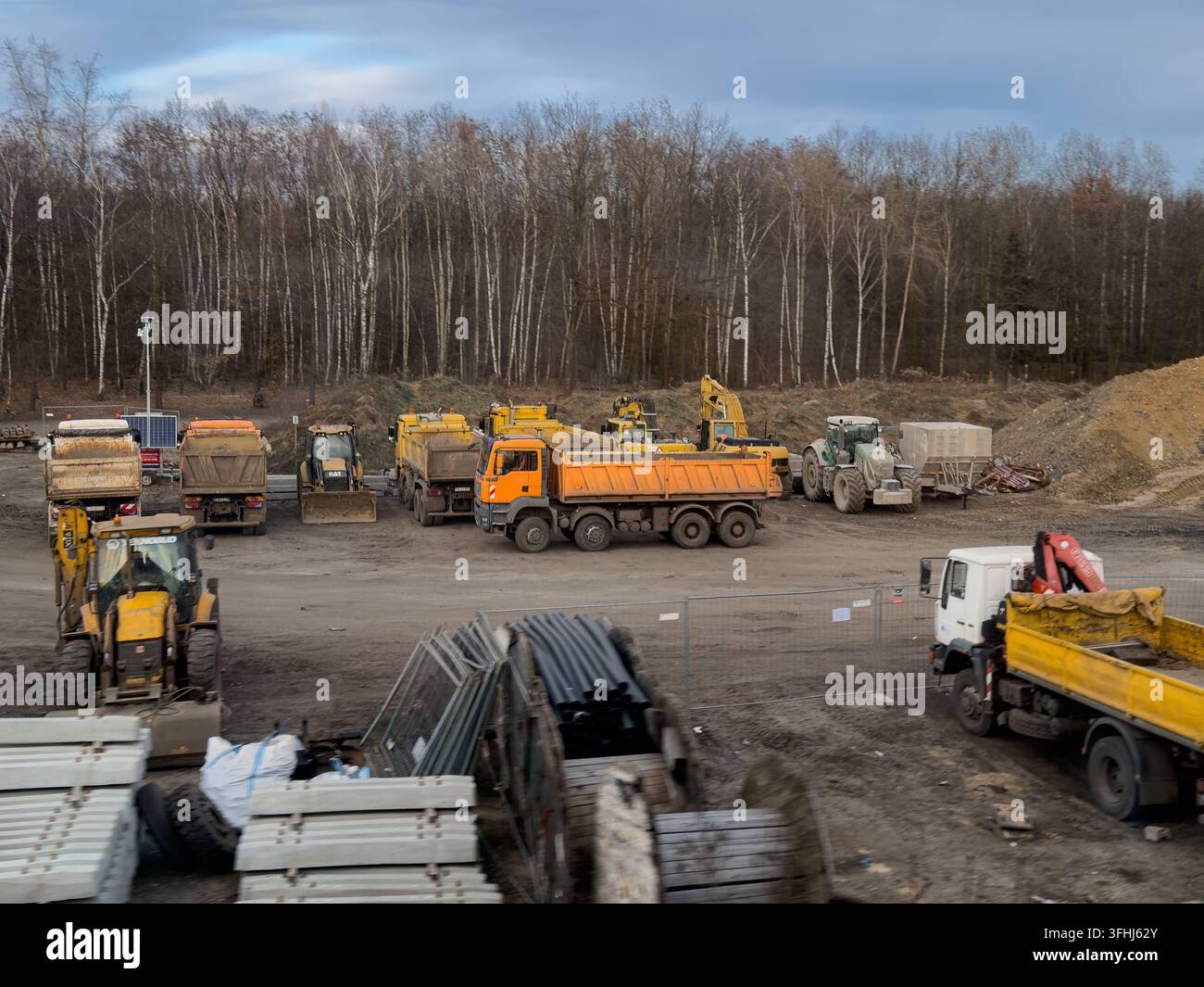Wroclaw, Polonia – 8 marzo 2026: Attrezzature per lo spostamento della terra, compresi camion ribaltabili e trattori, rimangono inattivi sulla terra a un progetto infrastrutturale con cumuli o Foto Stock