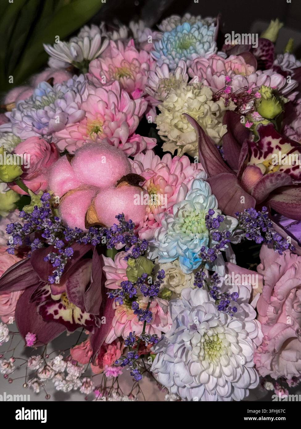 Una miscela elegante di fiori colorati tra cui capsule di cotone rosa, crisantemi a strati e orchidee maculate progettate per creare un'atmosfera romantica Foto Stock