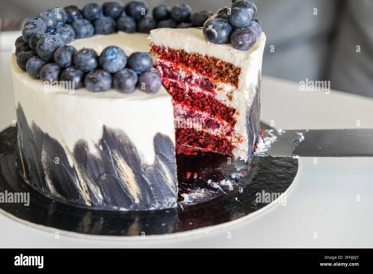 Il dolce decadente presenta strati rossi vivaci con ripieno di panna sormontato da succose bacche, creando così un attraente centrotavola da dessert per una società di alto livello Foto Stock