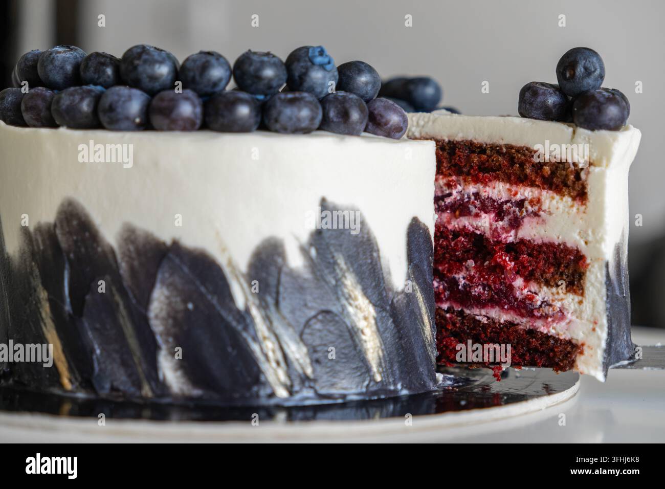 La torta red velvet affettata mostra strati umidi distinti con ripieno cremoso e glassa dipinta con maestria, offrendo un centrotavola sofisticato per par Foto Stock