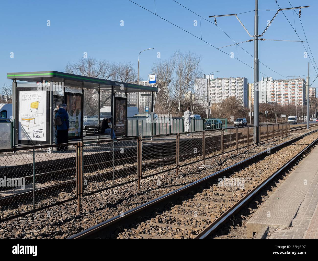 Poznań, Polonia – 4 marzo 2026: Pendolari in attesa a una fermata del tram cittadino accanto ai binari ferroviari, evidenziando la mobilità urbana, la connettività del trasporto e il Ro Foto Stock