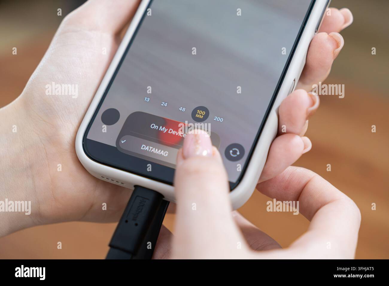 Utente che gestisce lo spazio di archiviazione mobile selezionando file su un telefono collegato a un SSD portatile, dimostrando un backup senza interruzioni dei contenuti digitali e una rapida organizzazione dei file Foto Stock