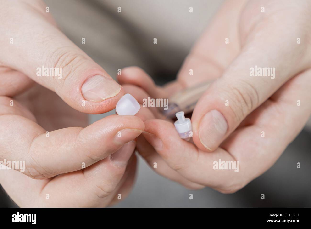 Mani vicine manipolano un minuscolo componente in plastica di un apparecchio acustico, offrendo una visione della manutenzione delle attrezzature mediche personali e del design della tecnologia di accessibilità Foto Stock