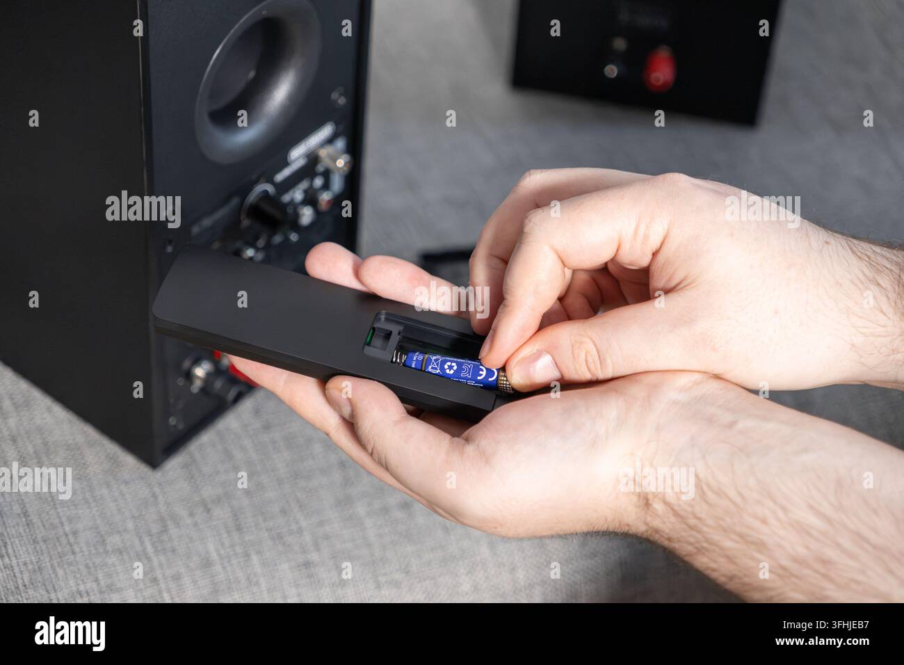 Le mani installano una nuova cella di alimentazione in un controller senza fili, dimostrando il rapido processo di preparazione dei dispositivi domestici elettronici per prestazioni affidabili Foto Stock