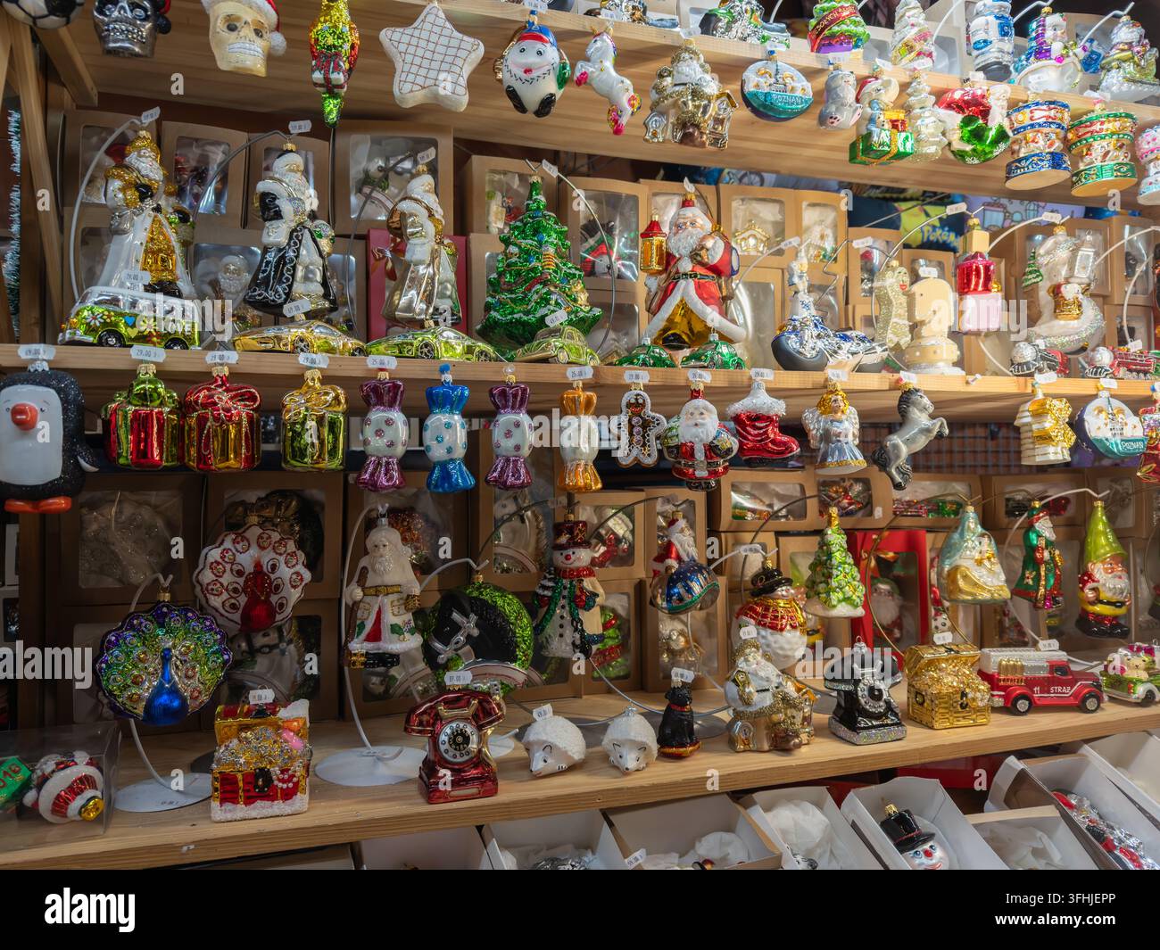 Varie palline di Natale in vetro colorate e figurine festive disposte su uno scaffale di vendita al dettaglio, rappresentando un mercato natalizio che offre decorazioni g Foto Stock