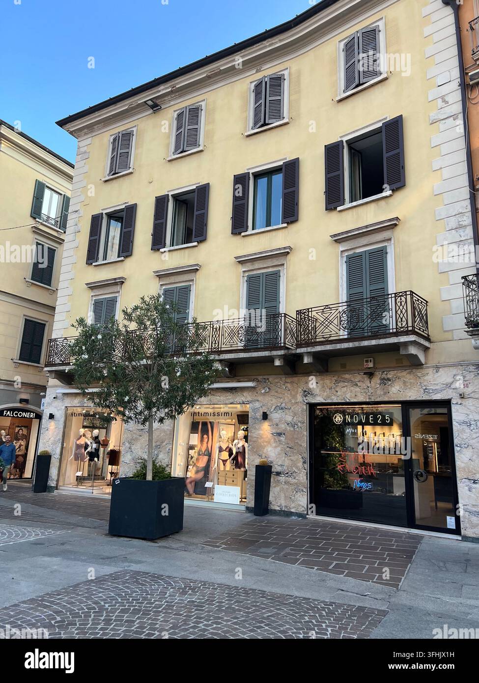 Via dello shopping con negozi al dettaglio e facciate di edifici a Brescia, Italia - Immagine stock catturata con smartphone