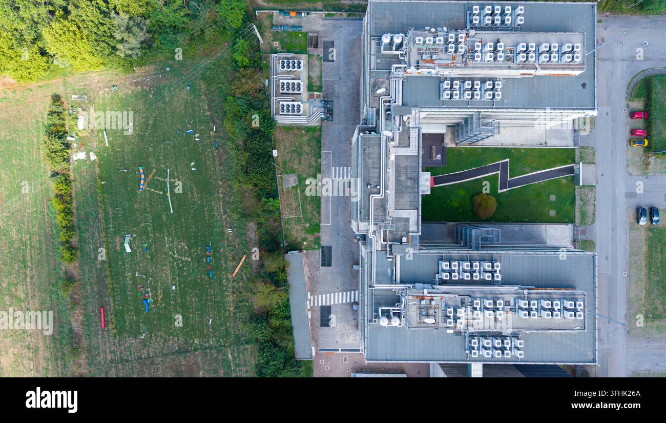 Vista aerea di una struttura di fornitore di servizi Internet con unità HVAC sul tetto e un'area di addestramento cani all'aperto adiacente con attrezzature per l'agility in Foto Stock