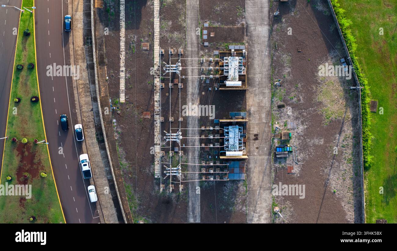 Vista aerea di una sottostazione elettrica con trasformatori e linee elettriche, situata accanto a una strada con auto in movimento a Posadas, provincia di Misiones, Arg Foto Stock
