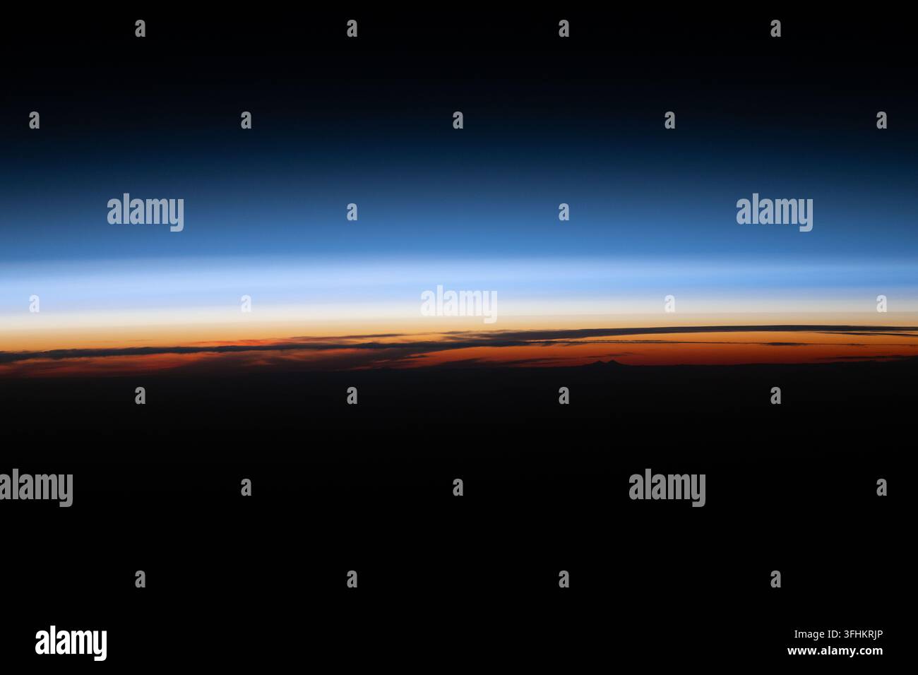 Un tramonto sotto l'orizzonte terrestre siluetta le nuvole e illumina l'atmosfera, 16 giugno 2026 Foto Stock