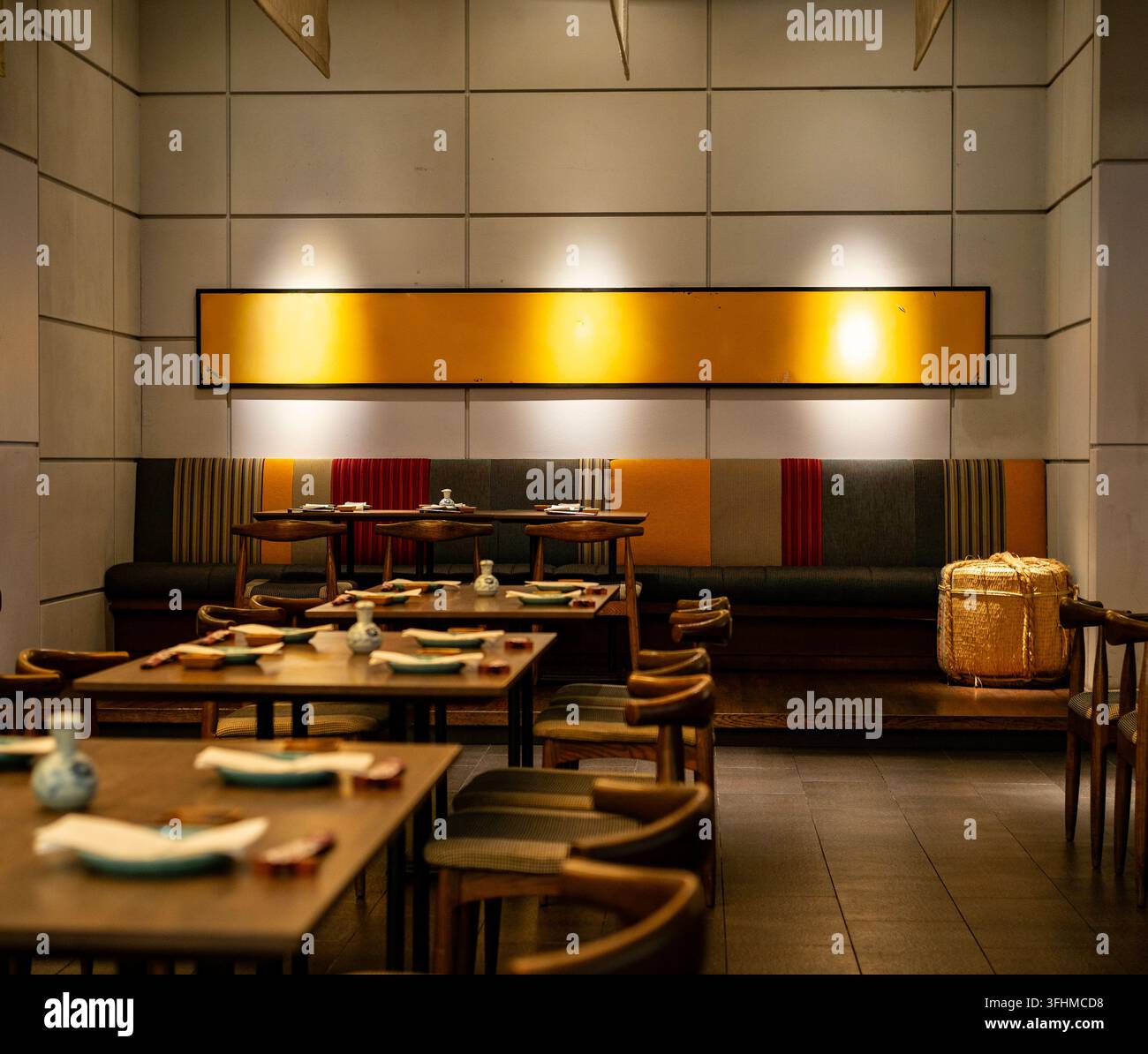 Interno moderno di ristorante giapponese con arte murale calda e configurazioni da pranzo in legno Foto Stock