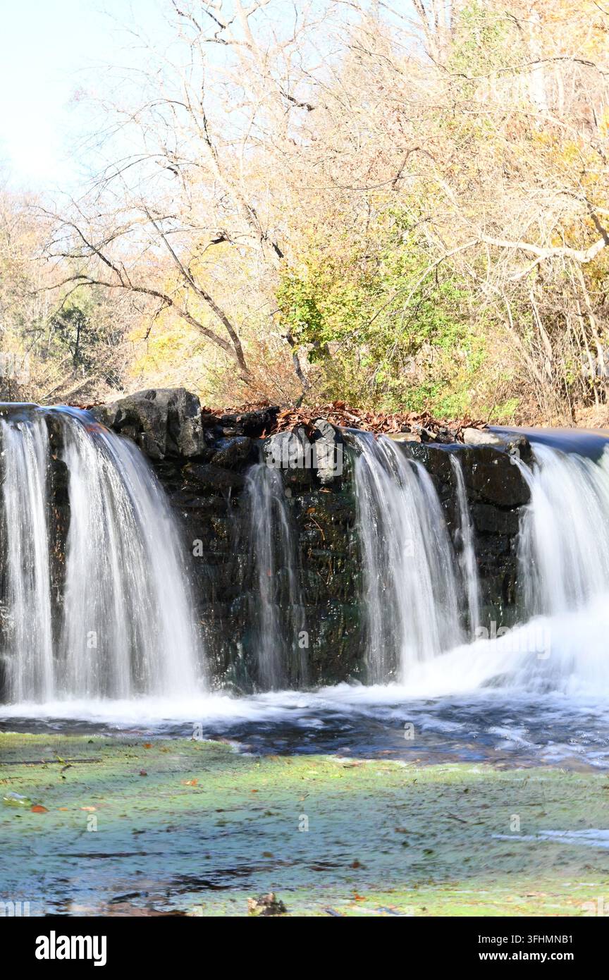 Cascata scenografica e diga in pietra nella foresta autunnale Foto Stock