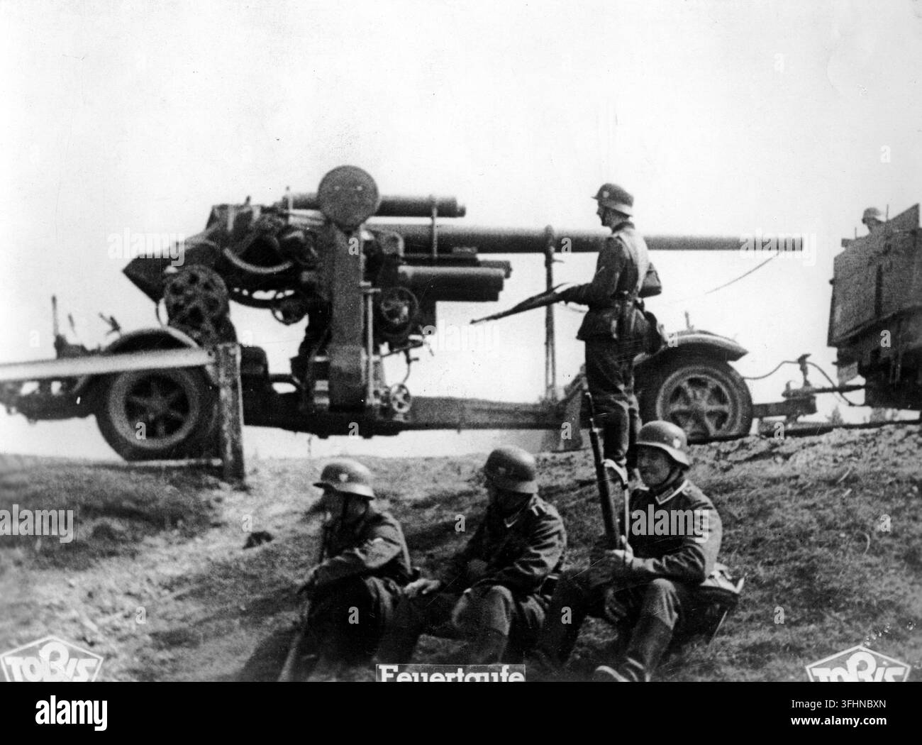 Un cannone antiaereo pesante Flak 18 da 88 mm, parte dell'artiglieria pesante tedesca, in una posizione di terrapieno rialzata, con quattro figure in elmetti e uniformi, 1939-1945. Foto Stock