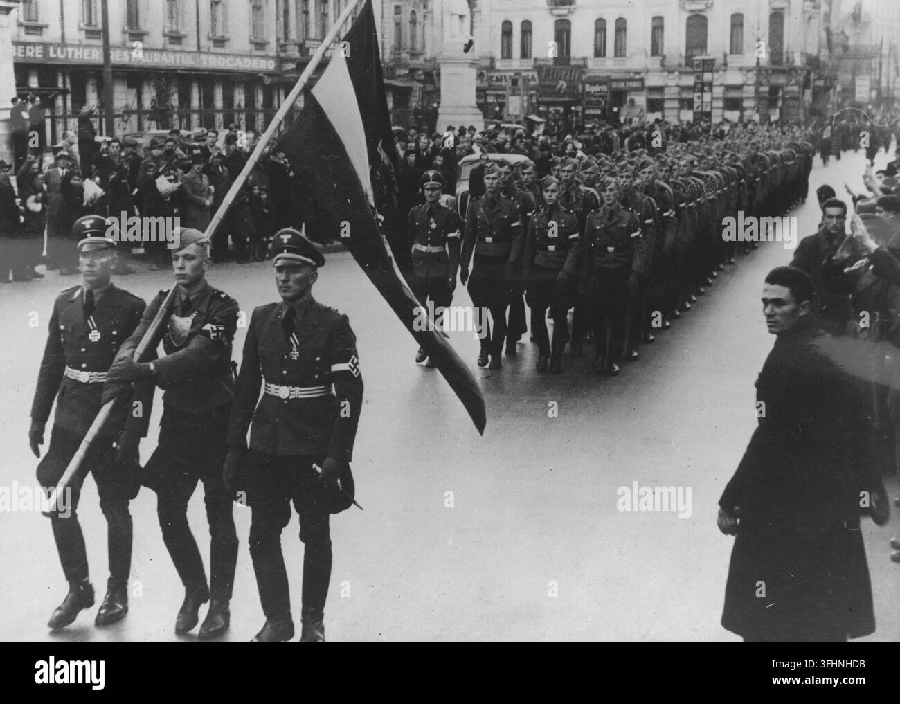 Delegazione della Gioventù hitleriana che sfila per le strade di Bucarest, novembre 1940, con una squadra colorata in testa e i residenti della città che guardano. Foto Stock