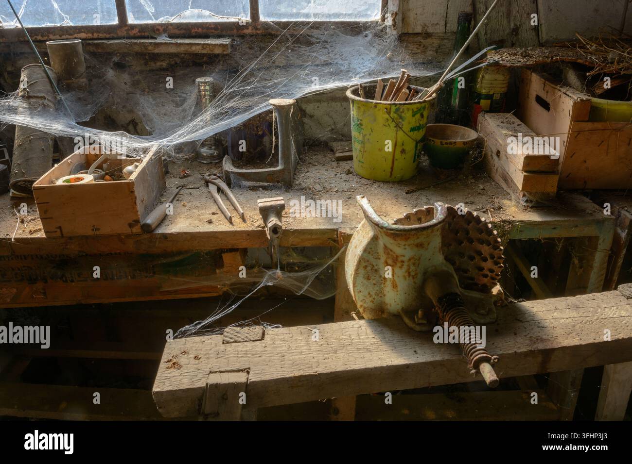 Vecchio laboratorio fai-da-te polveroso abbandonato con ragnatele, come se fosse congelato nel tempo. Foto Stock