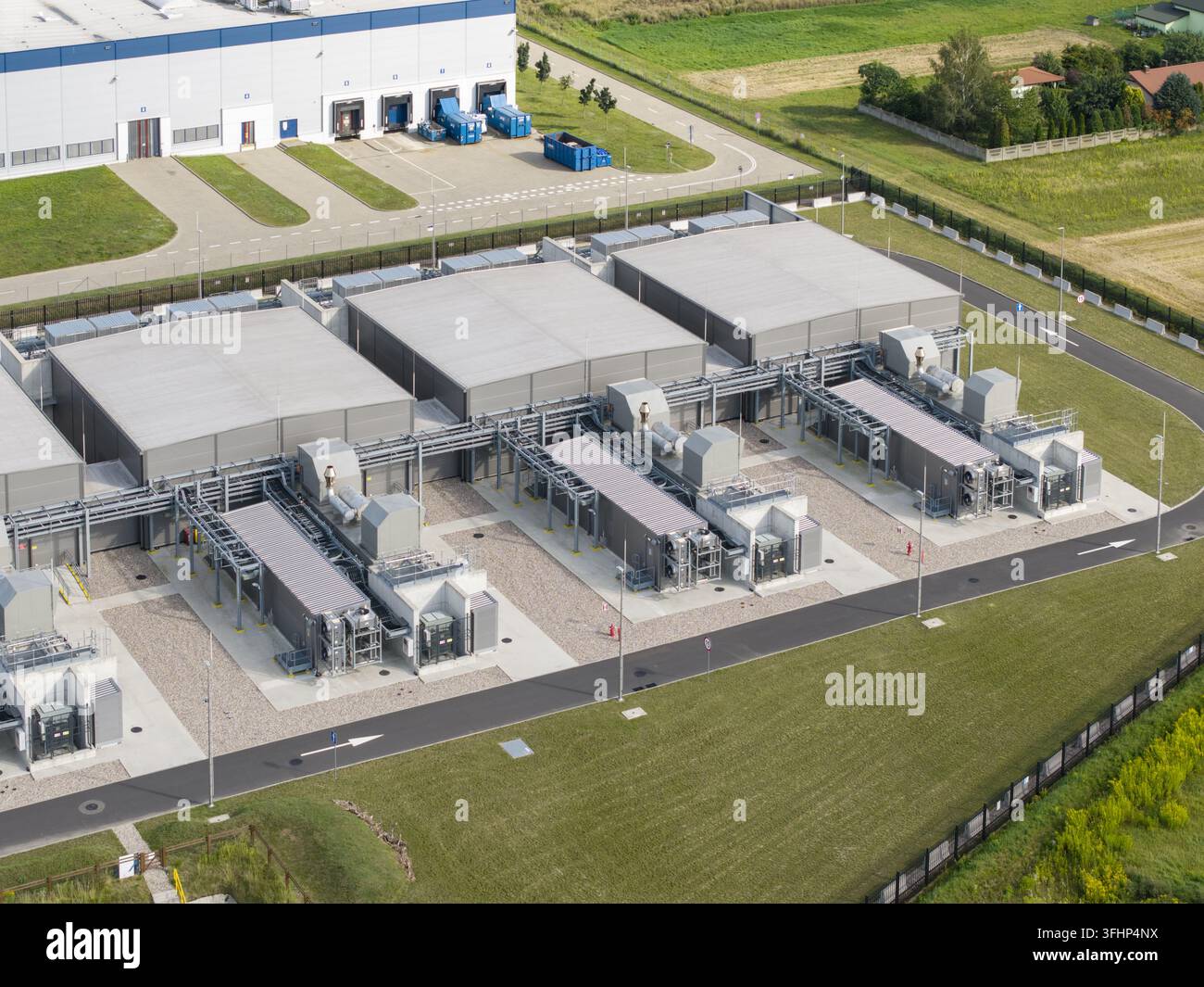 Vista aerea di una struttura tecnologica moderna con estesi sistemi di raffreddamento esterni, aree verdi progettate e strade di accesso dedicate, evidenziando i dati Foto Stock