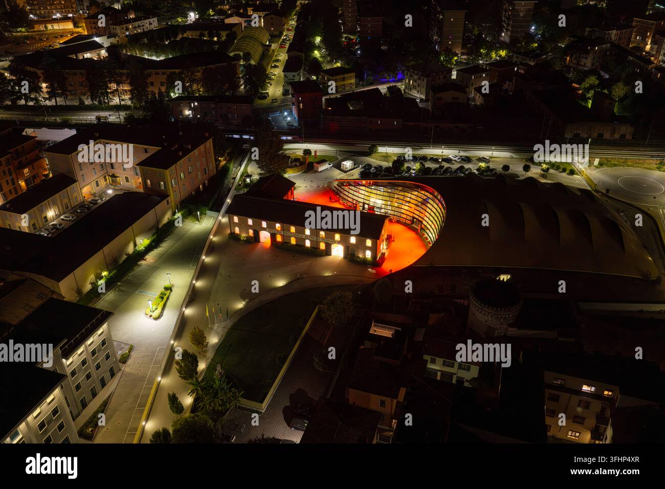 Vista aerea del museo Enzo Ferrari illuminato di notte con il suo caratteristico tetto giallo e l'architettura moderna a Modena, Emilia-Romagna, Italia. Foto Stock
