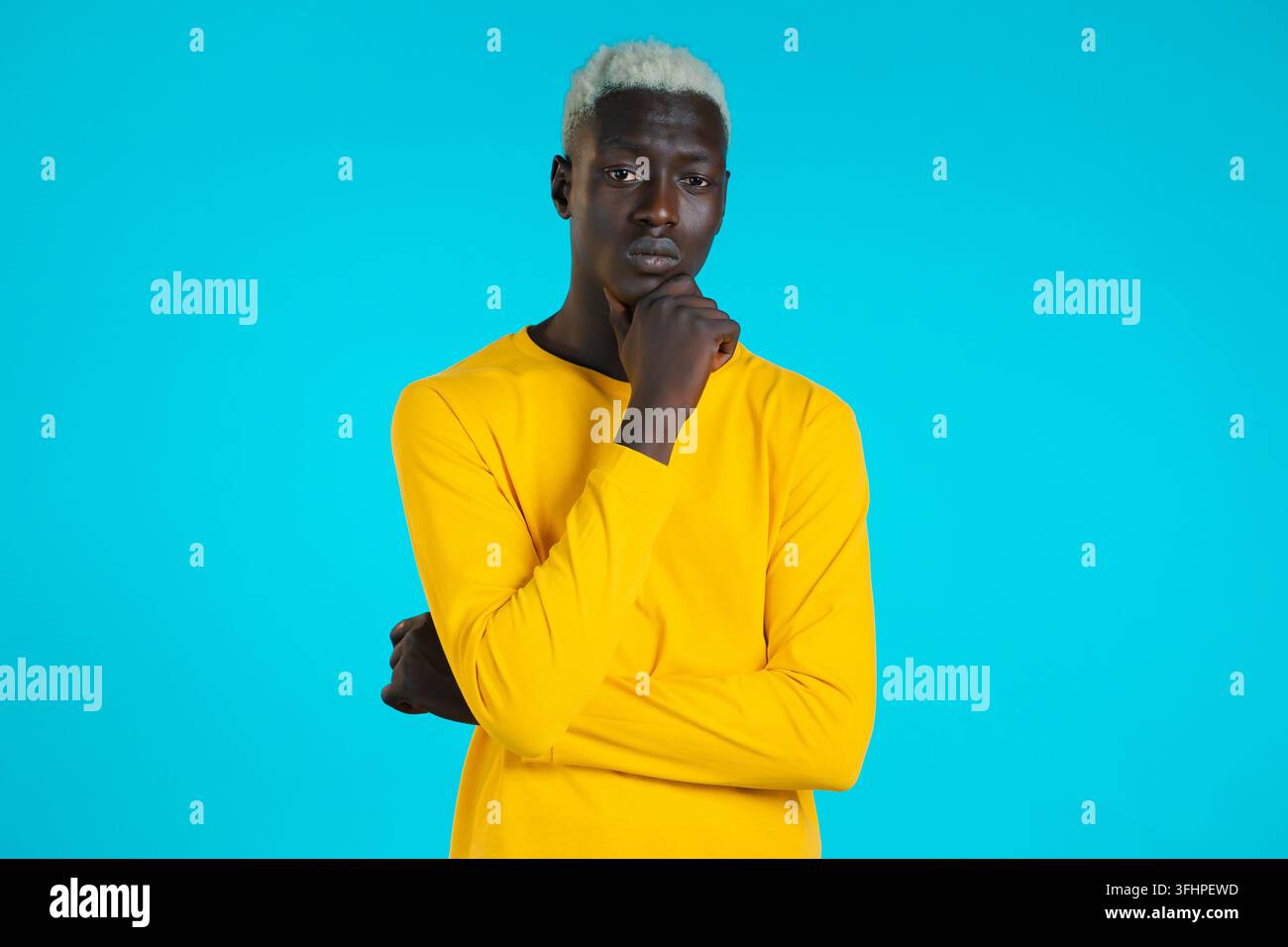 Uomo africano che pensa alla macchina fotografica su sfondo blu. Espressioni del volto pensivo. Bel modello nero maschio. Foto Stock