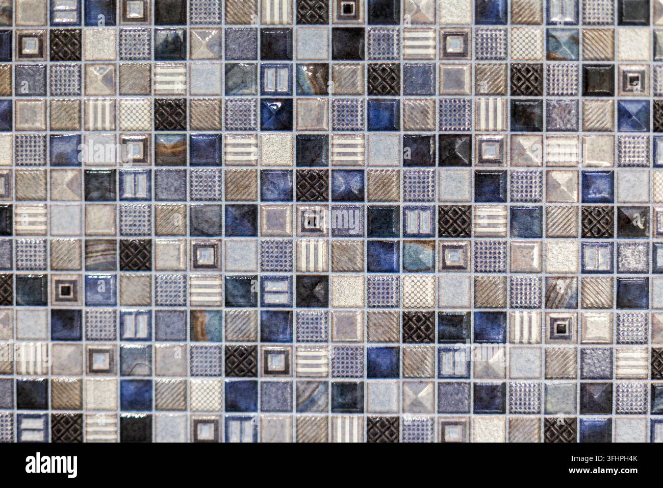 Motivo di piastrelle a mosaico geometriche blu e beige. Primo piano di piastrelle a mosaico blu, grigie, beige, nere e bianche con motivi geometrici, a righe e testurizzati vari Foto Stock