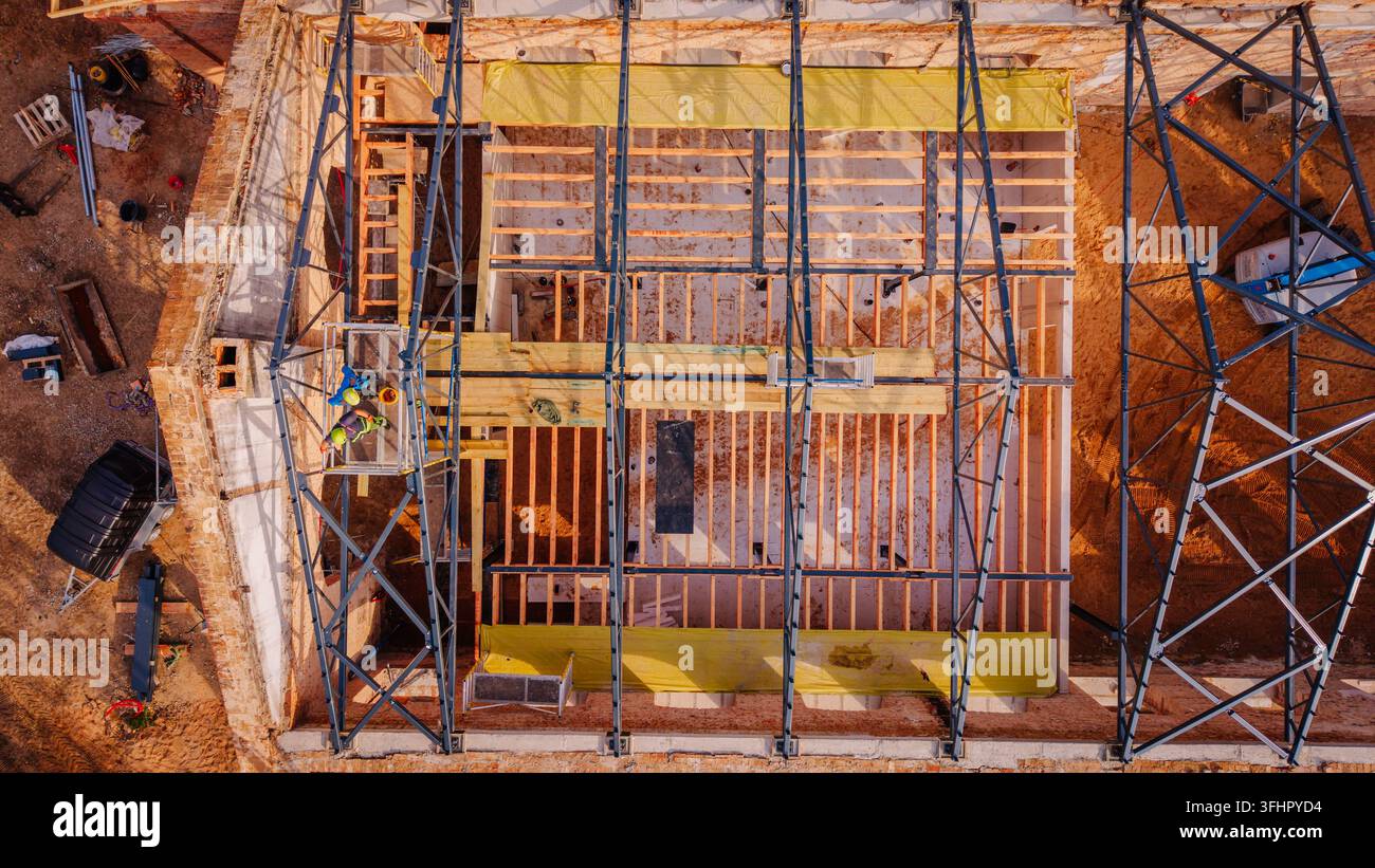 Valmiera, Lettonia - 09 settembre 2026: Veduta aerea di un cantiere di ristrutturazione edilizia con una struttura in acciaio, travi del tetto in legno, telo giallo e operai sul Foto Stock