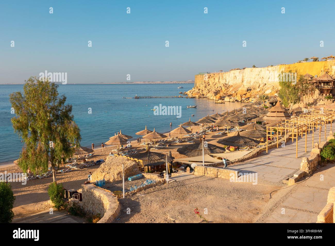 Vista panoramica della spiaggia di Ras Umm El Sid. Splendido alba sul Mar Rosso con rive rocciose, spiaggia sabbiosa con ombrelloni e primo r Foto Stock