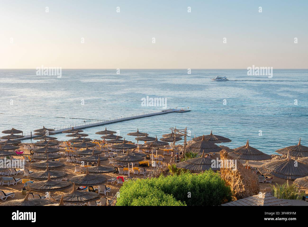 Vista panoramica della spiaggia di Ras Umm El Sid. Splendido alba sul Mar Rosso con rive rocciose, spiaggia sabbiosa con ombrelloni e primo r Foto Stock