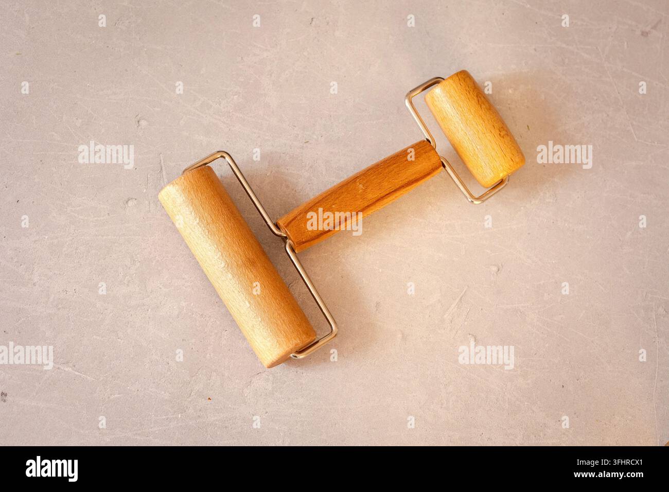 Rullo in legno a due lati per stendere impasti o argilla su un tavolo di marmo. Utensile di lavoro professionale. Disposizione piatta, vista dall'alto Foto Stock