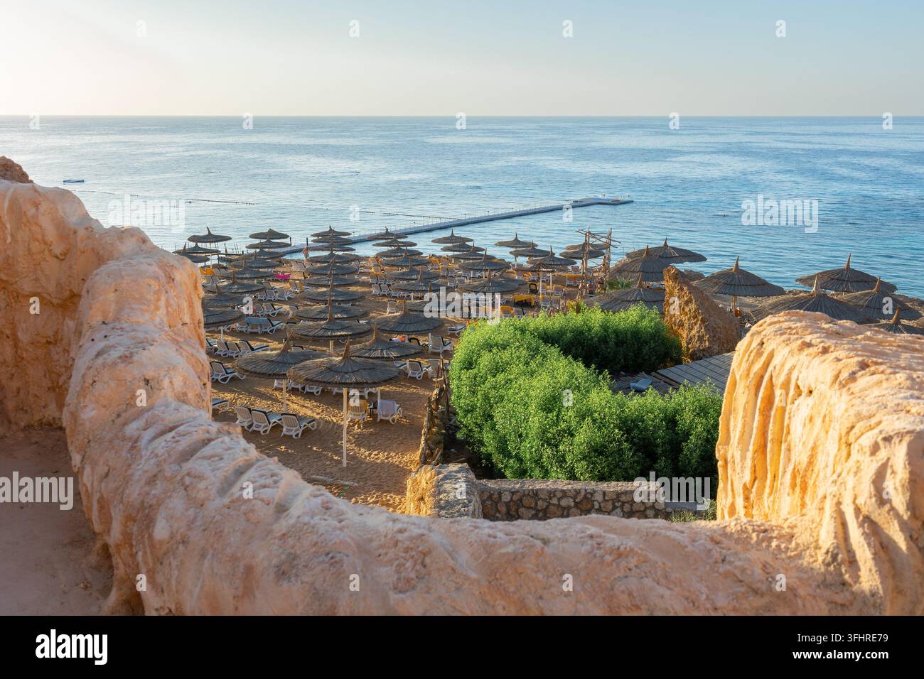Vista panoramica della spiaggia di Ras Umm El Sid. Splendido alba sul Mar Rosso con rive rocciose, spiaggia sabbiosa con ombrelloni e primo r Foto Stock