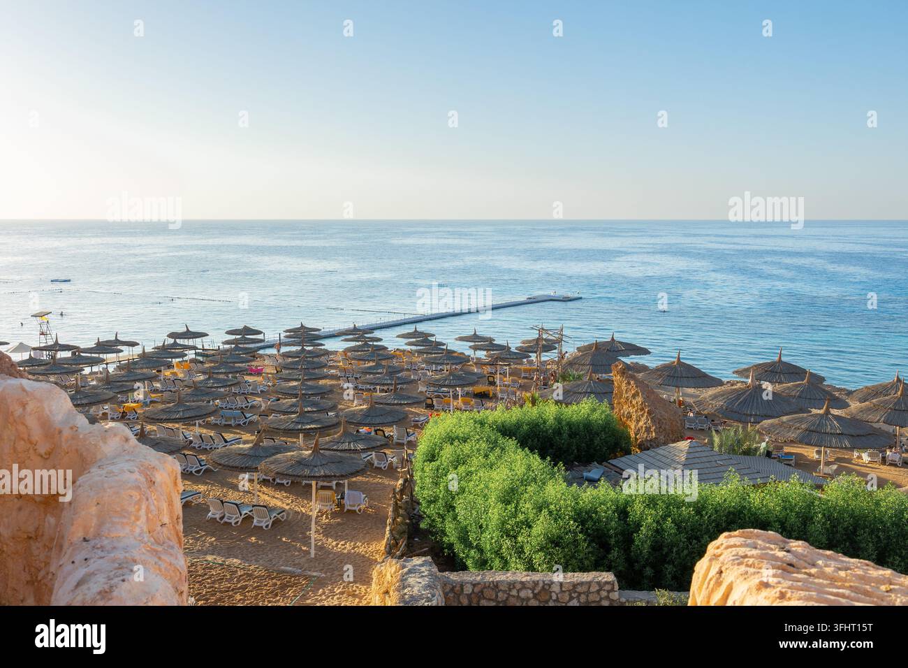 Vista panoramica della spiaggia di Ras Umm El Sid. Splendido alba sul Mar Rosso con rive rocciose, spiaggia sabbiosa con ombrelloni e primo r Foto Stock
