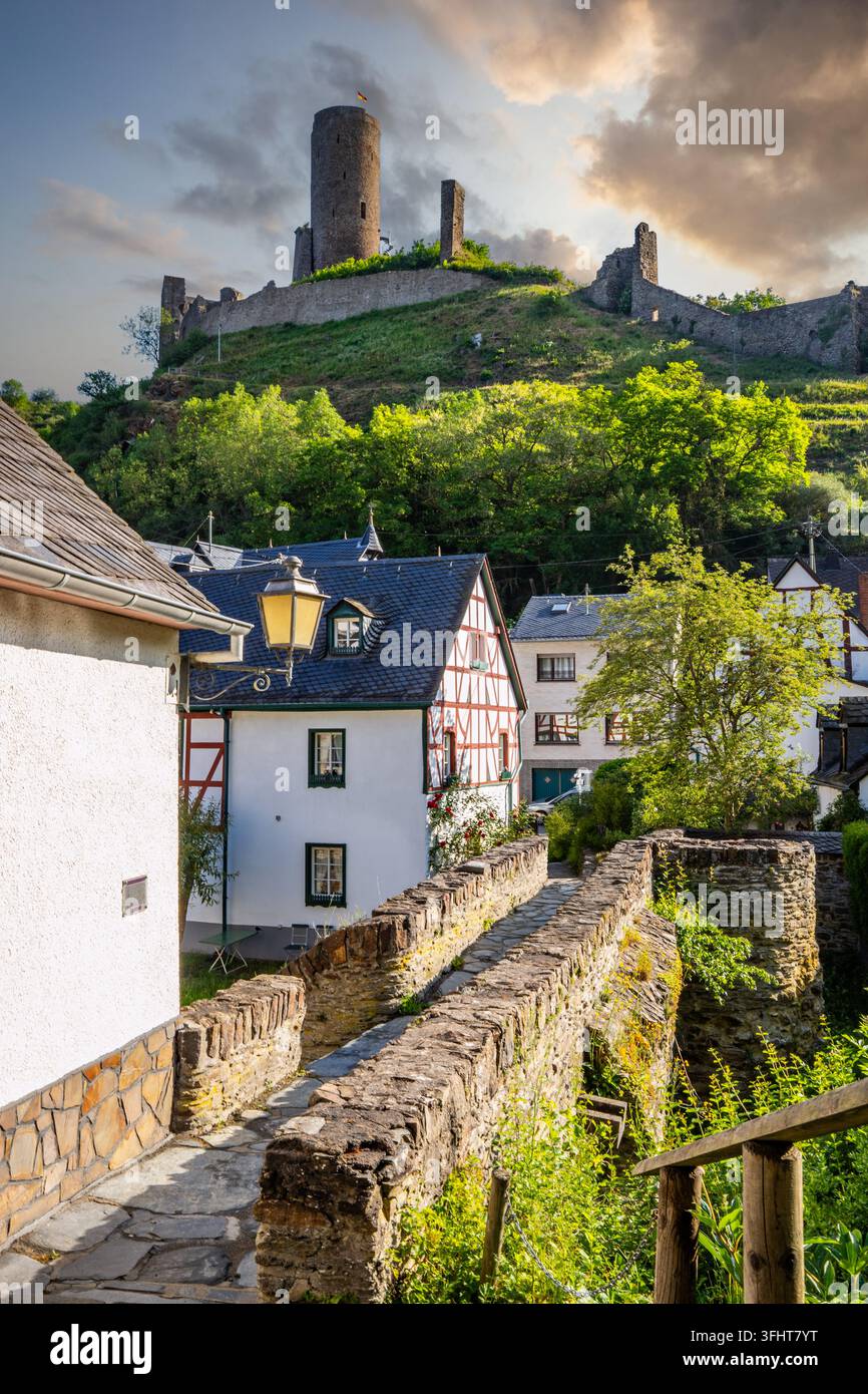 Paesaggio di un villaggio in legno lungo un fiume, circondato da colline e un castello. Città di Monreal sull'Elzbach, Germania Foto Stock